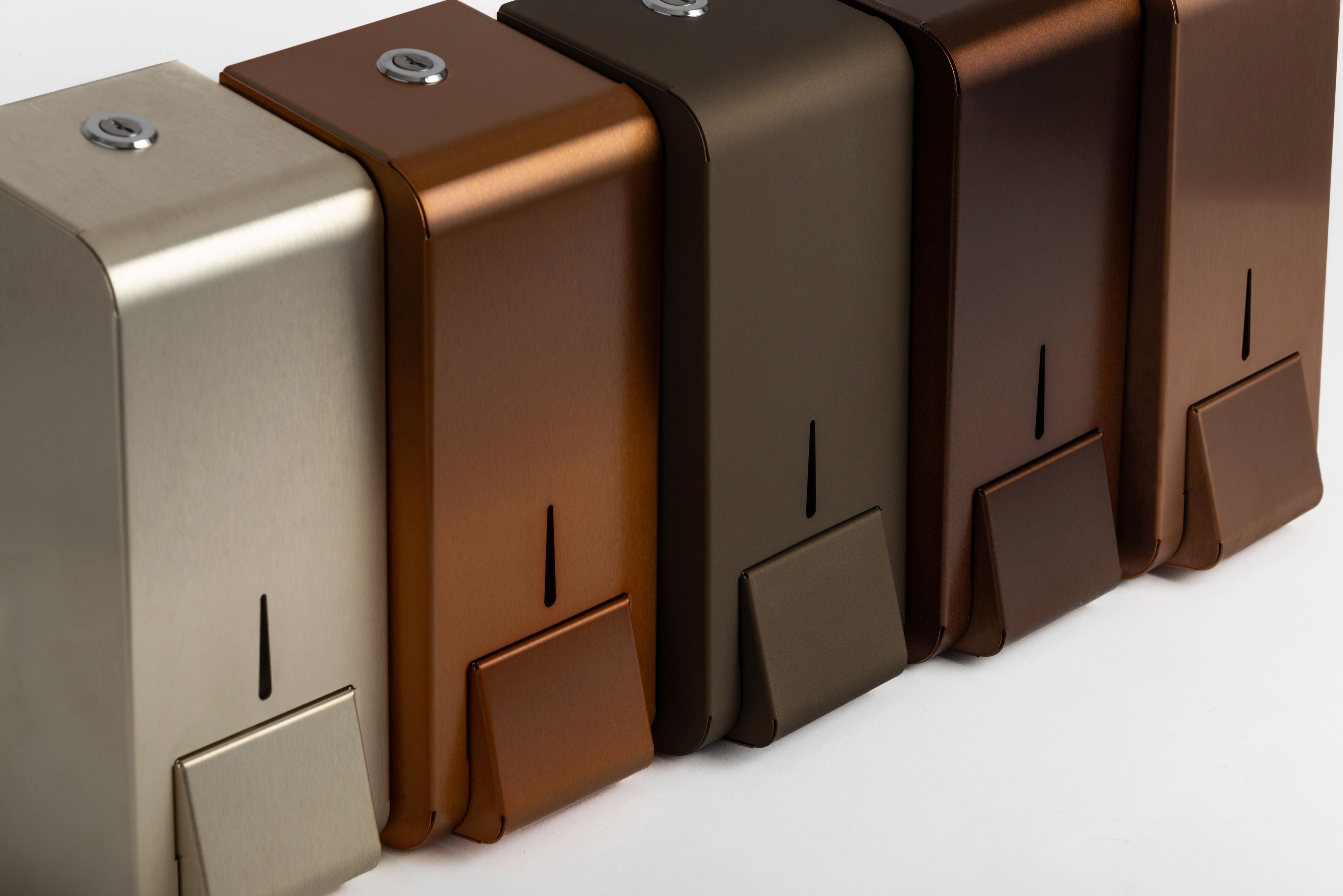 Billede af Opal serien designer range sæbedispensere i stål placeret ved siden af hinanden. På billedet er forskellige belægninger herunder PVD champagne, keramisk belægning, kobber.